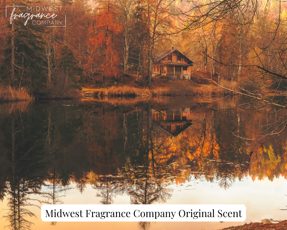 A cottage reflected in a lake amid fall foliage depicting a fragrance called Autumn Cottage.