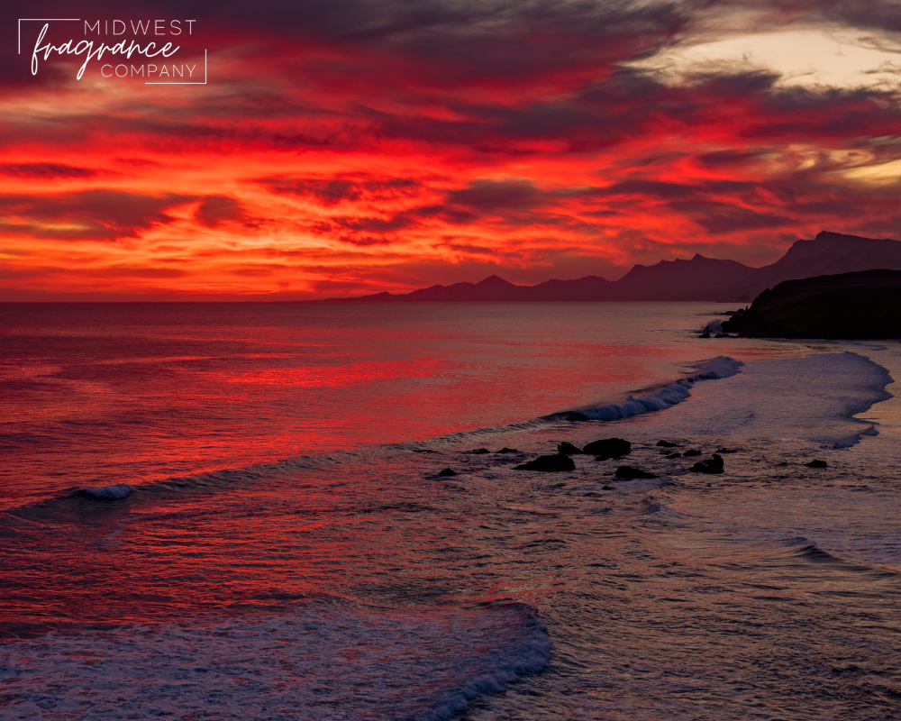 A vivid ocean sunset in shades of deep red, orange, and grey depicting a fragrance called Bom Dia Bright Cheirosa 40, a duplication scent by Sol de Janeiro.