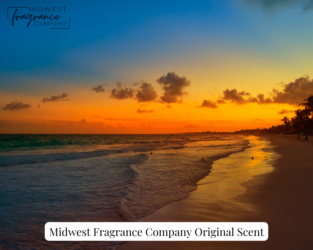 A troical sunset of beautiful orange and blue over a calm ocean and sand beach depicting the fragrance Sunset Citrus.