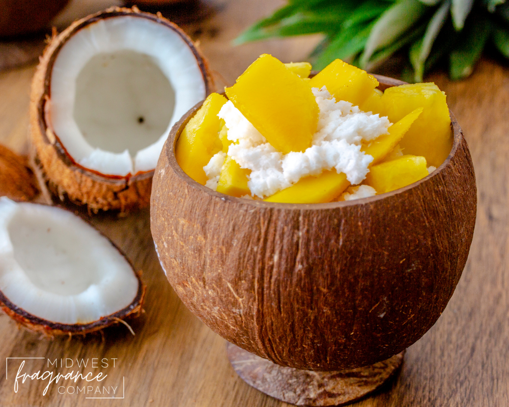 A round wooden bowl filled with sliced mango and coconut milk with a cut coconut in the background on a rustic wood surface.