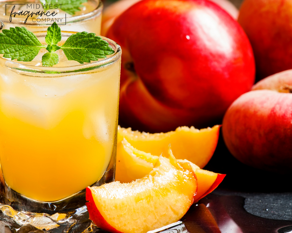 Clear glass of peach nectar with mint leaves and whole and cut peach slices.