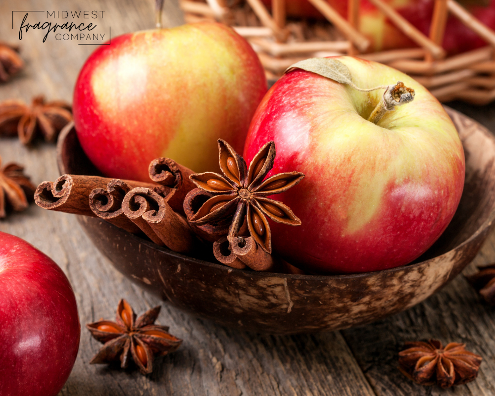 Apple essential oil on a wooden table near ripe red apples. Essential oil  is used to fill lamps, perfumes and in cosmetics. Stock Photo