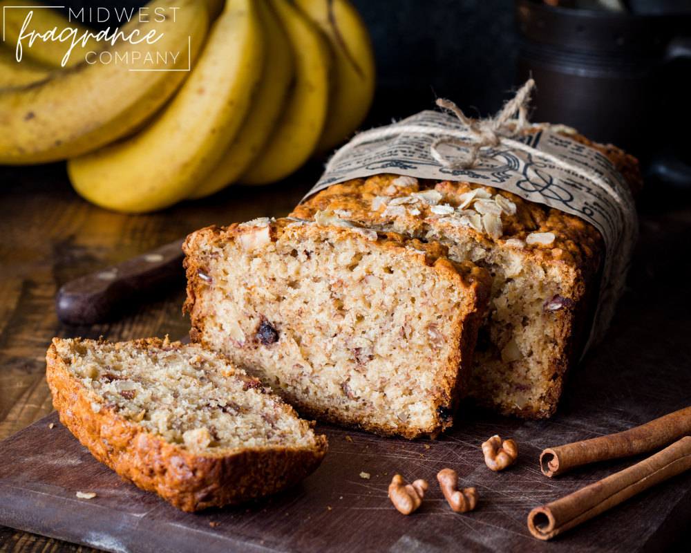 A loaf of freshly baked sliced banana nut bread with bananas, walnuts, and cinnamon sticks.