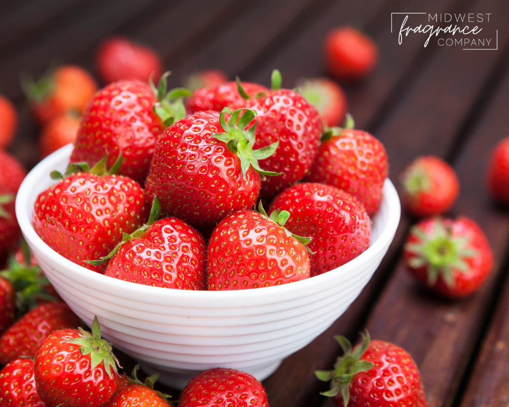 Sweet strawberries piled high in a white bowl and on a wooden table