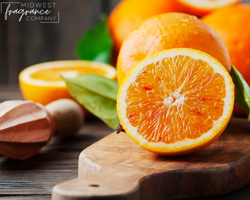 Whole and sliced oranges on a wood cutting board depicting a fragrance called Sweet Orange and Chili Pepper.