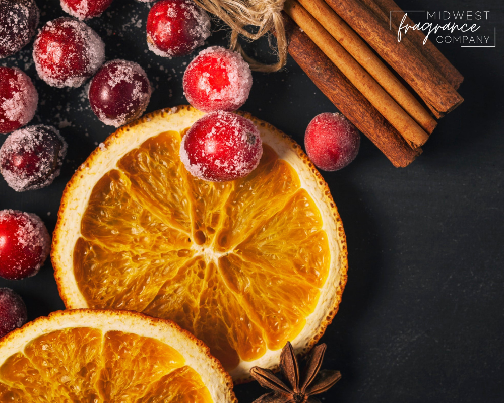 Ingredients to make orange cranberry spice bread including citrus slices, cranberries, cinnamon sticks, and clove on a dark background. 