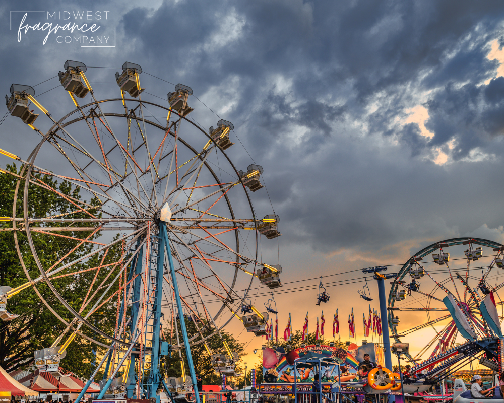 A summer boardwalk of carnival rides amid the setting sun and dark grey clouds.